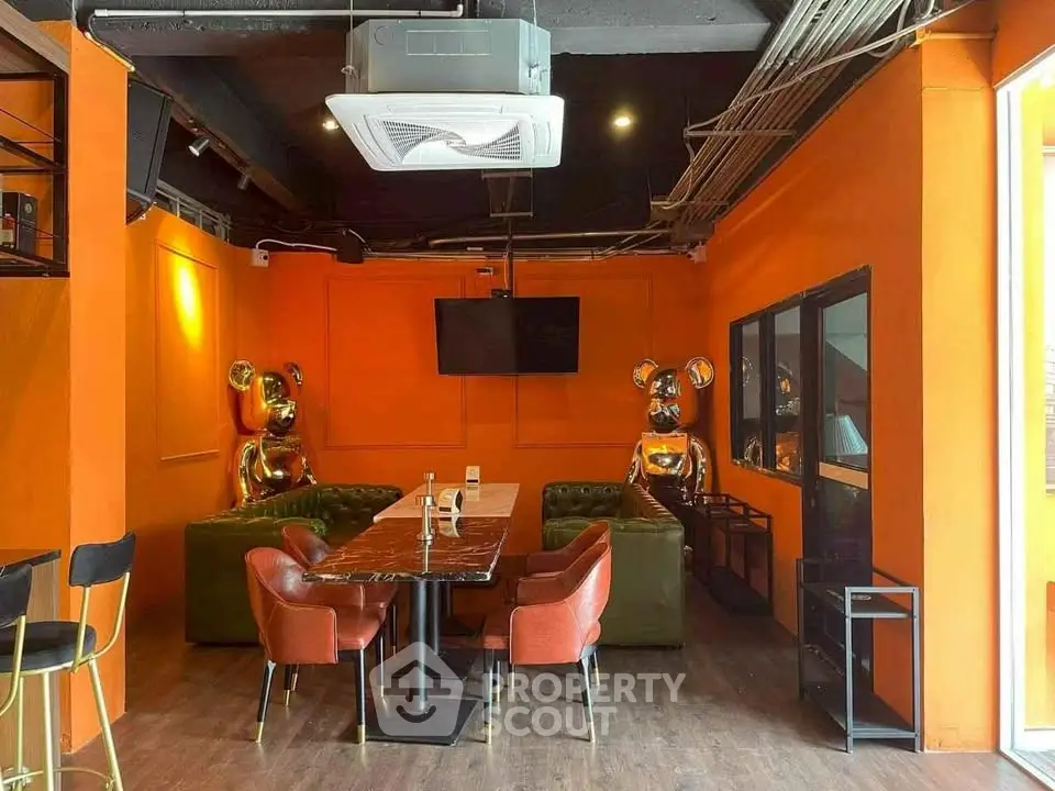 Stylish modern interior with vibrant orange walls, chic seating, and unique decor, perfect for trendy gatherings.