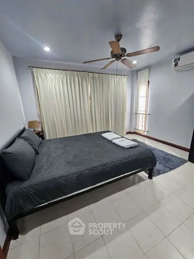Spacious bedroom with modern decor and ceiling fan, perfect for relaxation.