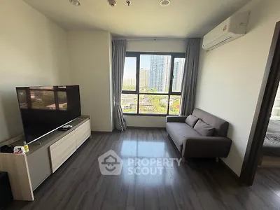 Modern living room with large window and city view, featuring sleek furniture and air conditioning.
