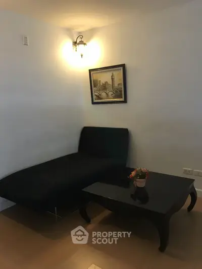 Cozy living room corner with stylish black furniture and elegant wall art.