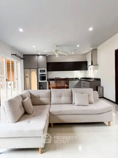 Modern open-plan living room with sleek kitchen and cozy sectional sofa, perfect for entertaining.