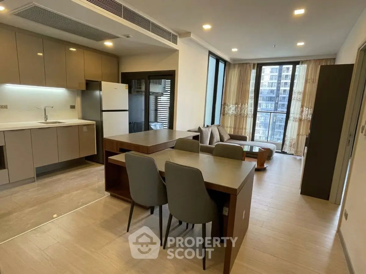 Modern open-plan kitchen and living area with sleek furniture and large windows.