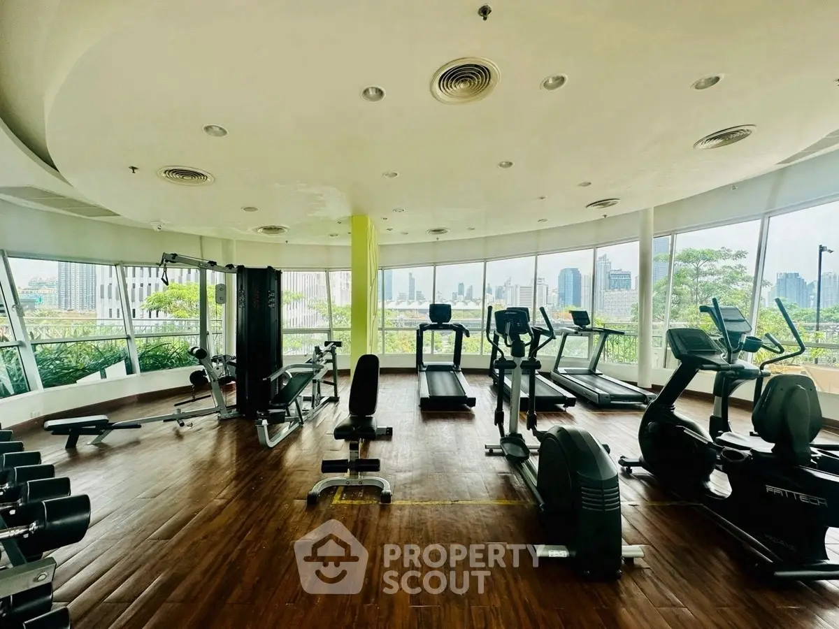 Spacious gym with modern equipment and panoramic city views, perfect for fitness enthusiasts.