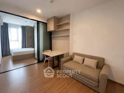 Modern studio apartment with cozy living area and bedroom separated by glass partition.