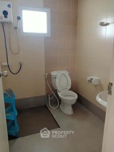 Compact bathroom with shower, toilet, and sink in neutral tones.
