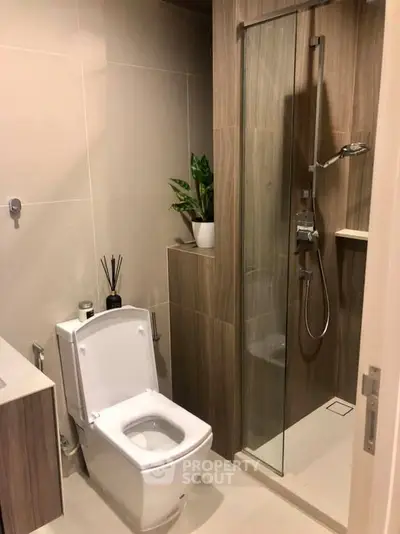 Modern bathroom with sleek shower and toilet design, featuring elegant wood paneling and contemporary fixtures.