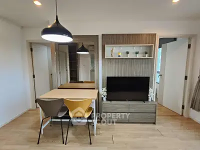 Modern living room with stylish dining area and sleek TV unit, featuring contemporary lighting and wooden flooring.