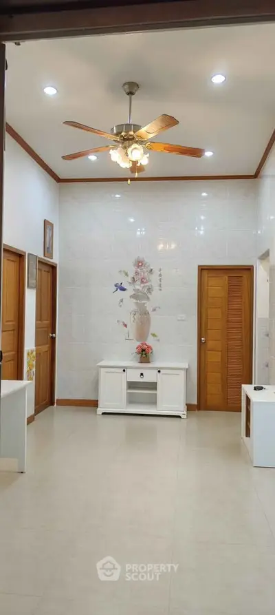 Elegant living room with ceiling fan and floral wall art, showcasing modern interior design.