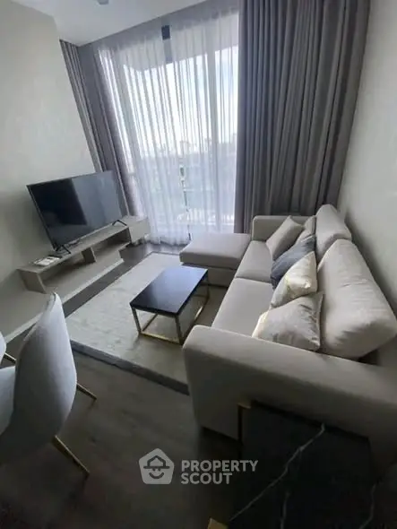 Modern living room with stylish furniture and large window offering natural light.