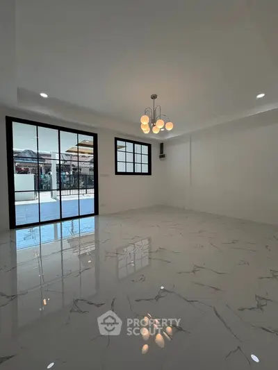 Spacious modern living room with marble flooring and elegant lighting, featuring large windows for natural light.