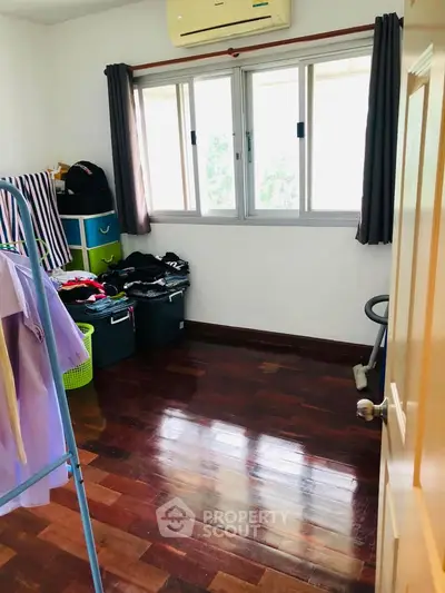 Cozy room with wooden flooring and ample natural light, perfect for a small bedroom or study area.