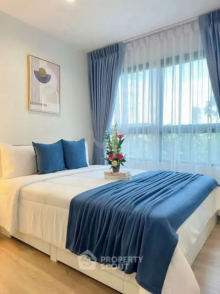 Elegant bedroom with blue accents and large window, perfect for relaxation.