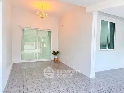 Spacious bright room with elegant chandelier and sliding glass doors