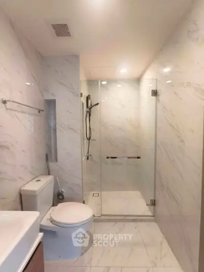 Modern bathroom with glass shower and marble tiles, sleek and elegant design.