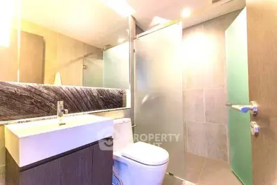 Modern bathroom with sleek fixtures and frosted glass shower doors.