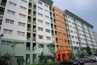 Modern multi-story apartment building with colorful facade and lush greenery.