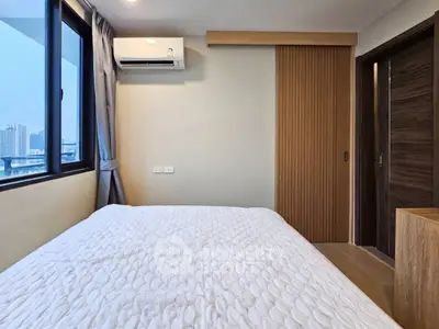 Modern bedroom with city view, featuring a cozy bed and sleek sliding door design.