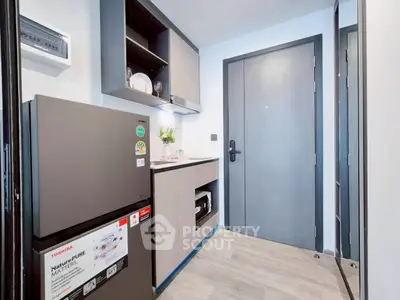 Modern compact kitchen with sleek appliances and stylish cabinetry in a contemporary apartment.