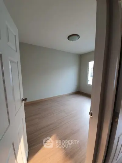 Spacious empty room with wooden flooring and natural light, perfect for customization.