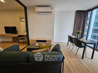 Modern living room with dining area and large windows in a stylish apartment.
