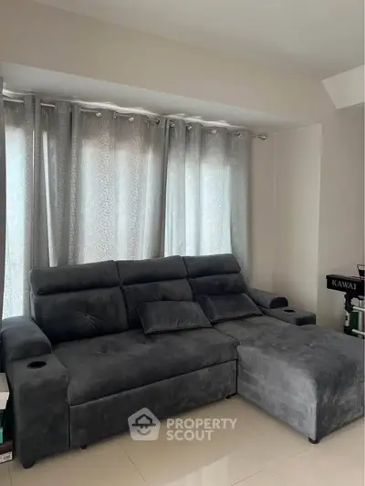 Spacious living room with plush gray sectional sofa and elegant curtains