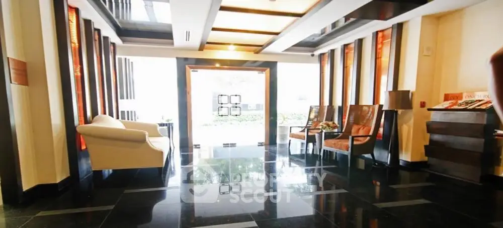 Elegant building entrance with modern seating and sleek black flooring.