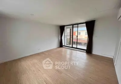 Spacious empty living room with large windows and wooden flooring.