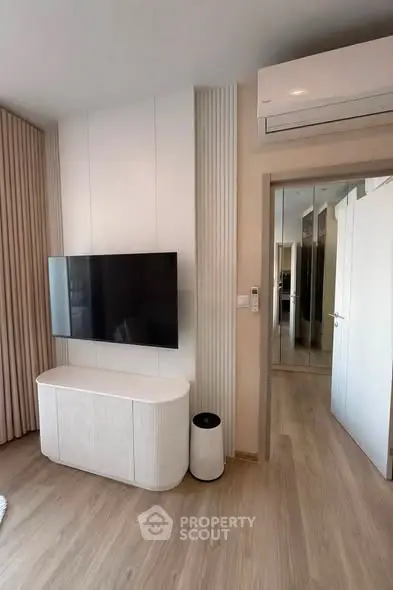 Modern living room with sleek TV setup and air conditioning, featuring elegant wooden flooring and stylish decor.