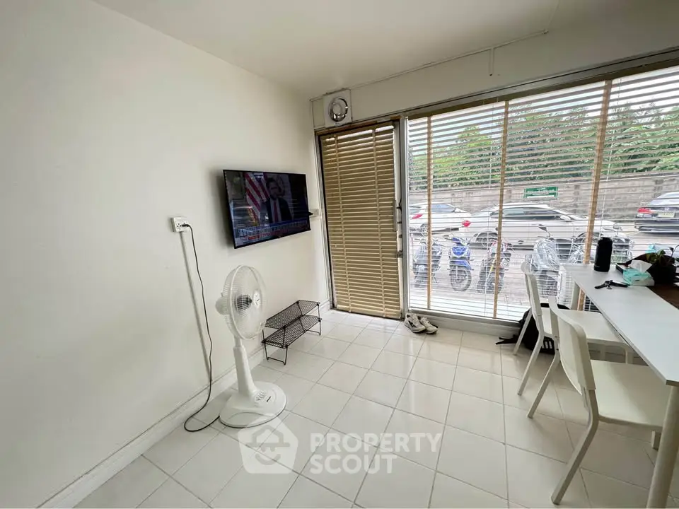 Bright living room with modern decor and large windows overlooking parking area.