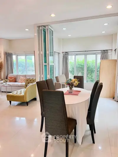 Spacious open-plan living and dining area with elegant decor and large windows.
