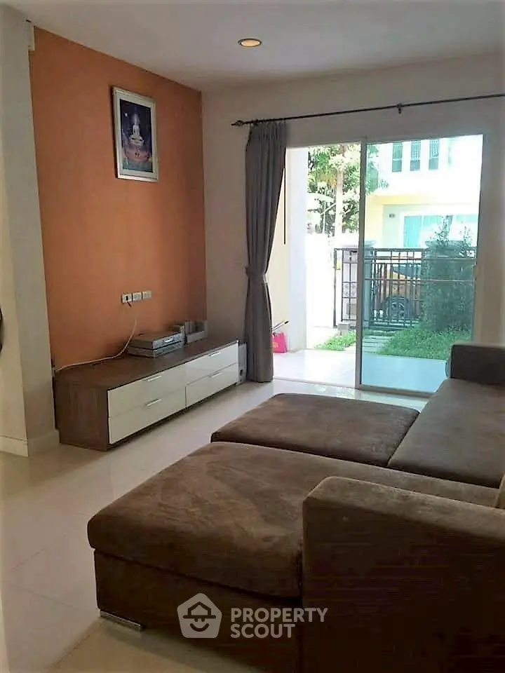 Cozy living room with sectional sofa and garden view through sliding glass doors.