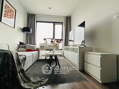 Modern living room with stylish decor and large TV, featuring cozy seating and natural light.