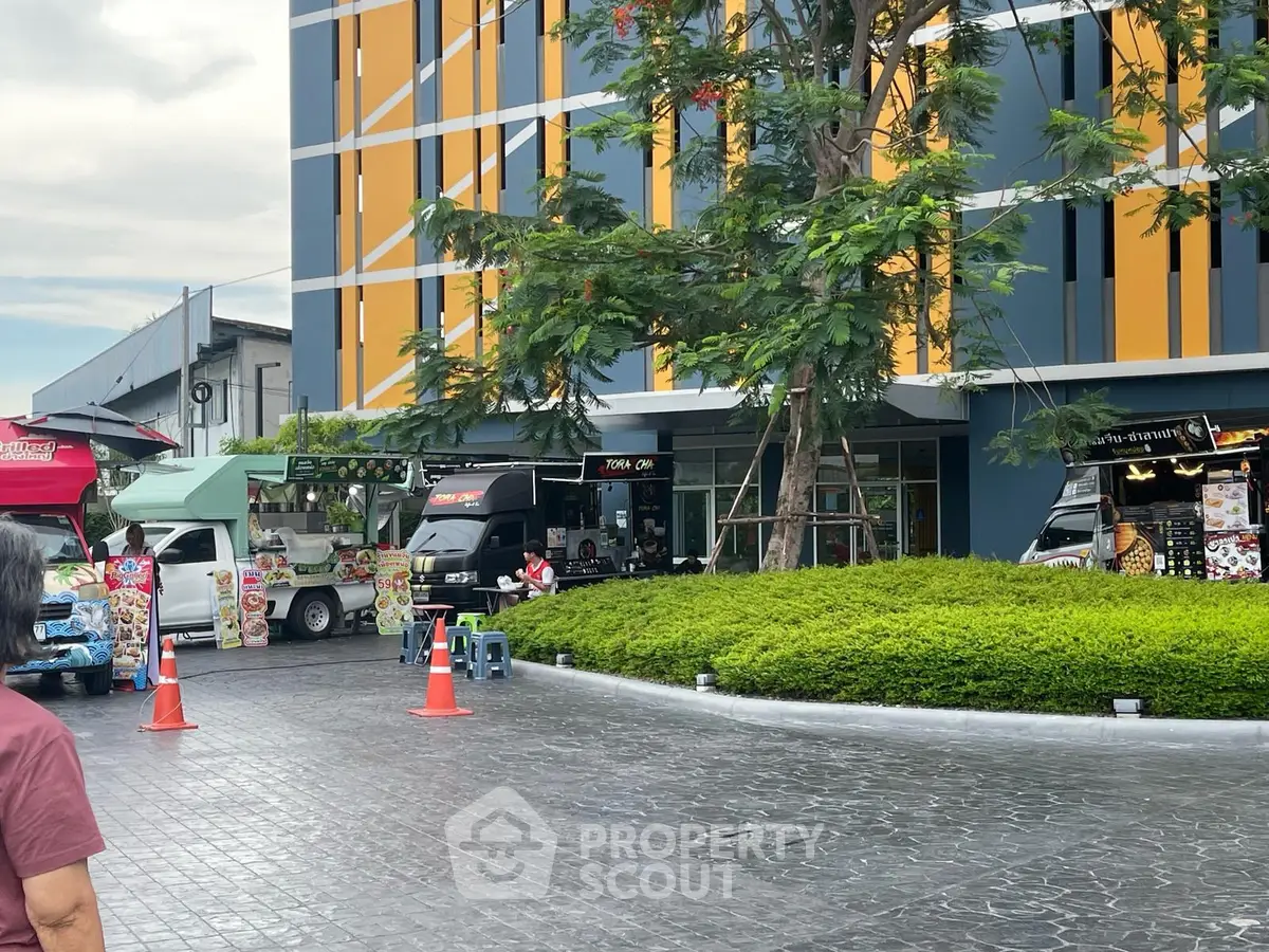 Modern building exterior with vibrant facade and food trucks in front, offering a lively urban atmosphere.