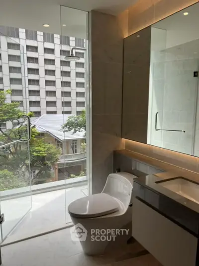Modern bathroom with glass shower and city view, featuring sleek fixtures and natural light.