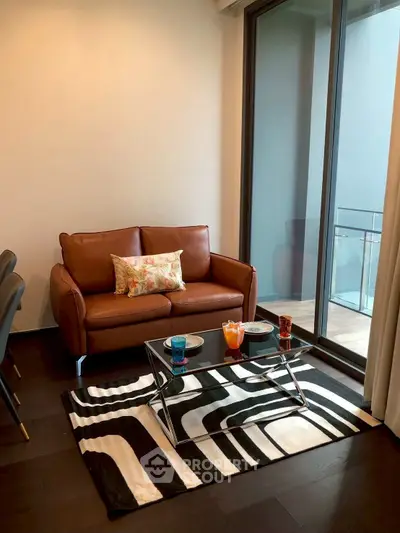 Stylish living room with leather sofa and glass coffee table, featuring a modern balcony view.
