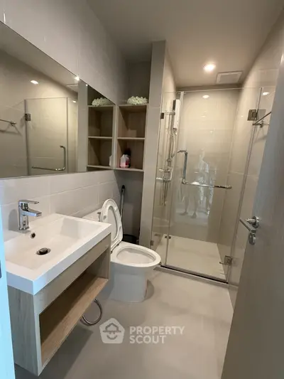 Modern bathroom with glass shower and sleek vanity in contemporary apartment.