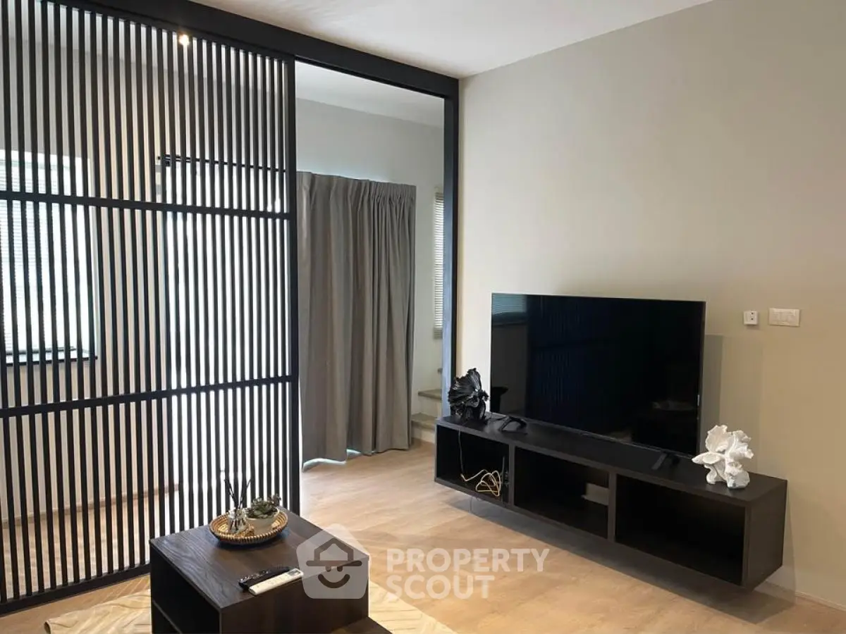 Modern living room with sleek TV stand and decorative elements, featuring a stylish partition and natural light.