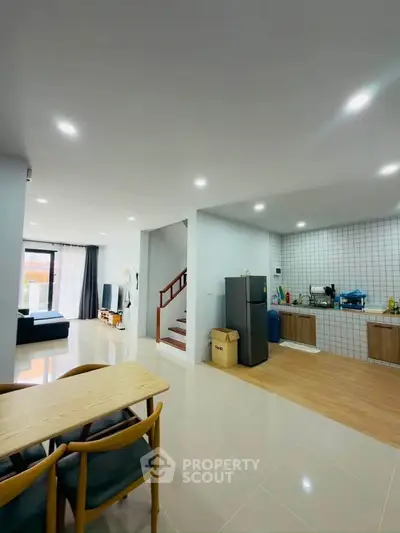 Spacious open-plan living room and kitchen with modern decor and ample natural light.