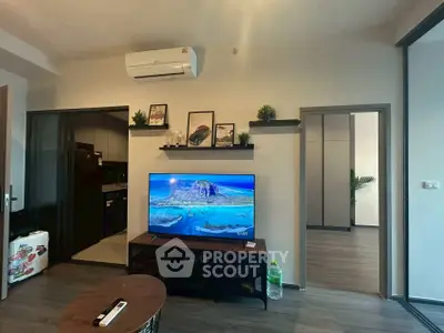 Modern living room with TV and air conditioning, open view to kitchen and bedroom.