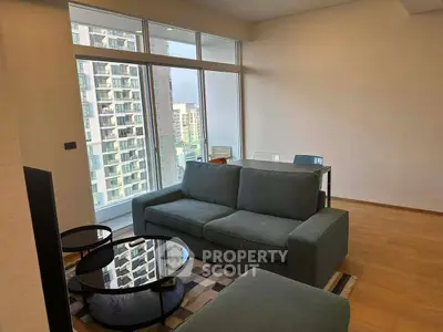 Modern living room with large windows and city view, featuring stylish furniture and wooden flooring.