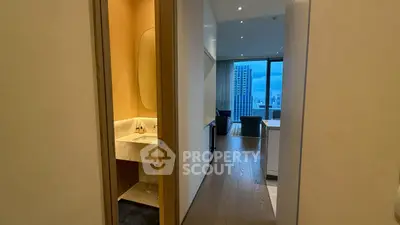 Modern apartment hallway with view of living room and cityscape through large windows.