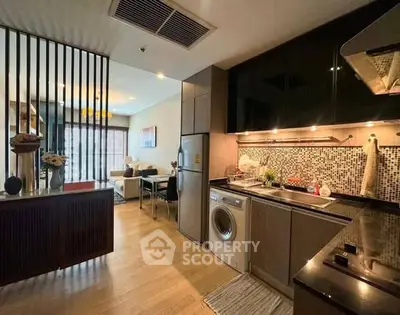 Modern open-layout kitchen with washing machine and stylish living area in a cozy apartment.