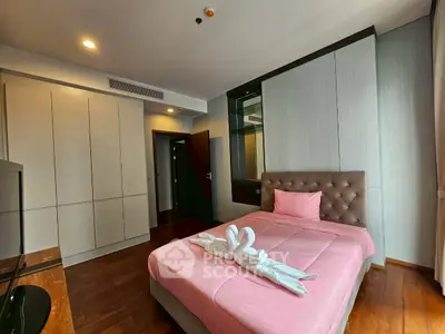 Cozy bedroom with pink bedding and modern wardrobe in stylish apartment.