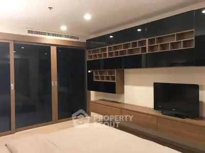 Modern bedroom with sleek black cabinetry and built-in TV unit, featuring ample storage and contemporary design.