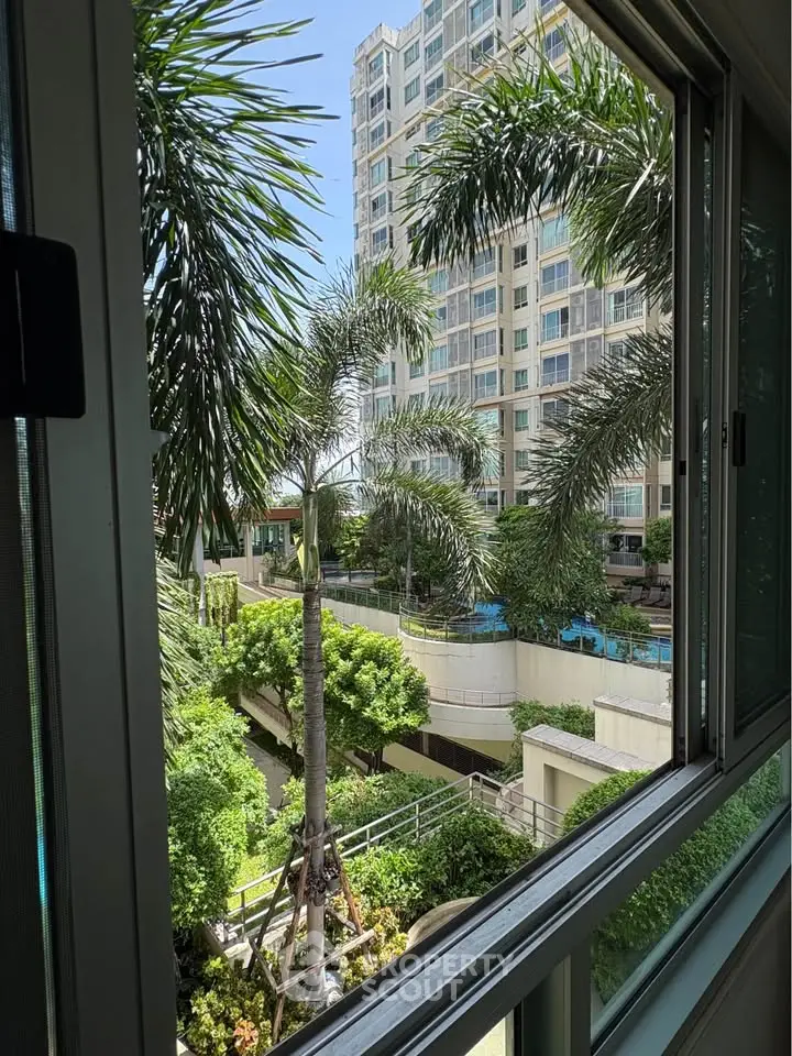 Stunning view from window overlooking lush garden and modern building exterior.