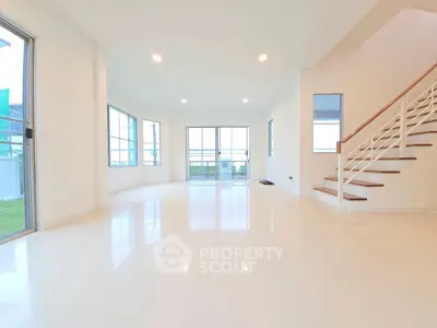 Spacious modern living room with large windows and sleek staircase