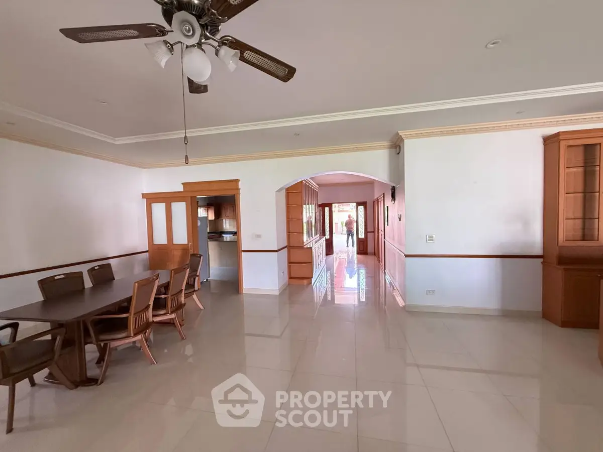 Spacious open-plan living and dining area with elegant wooden furniture and ceiling fan.