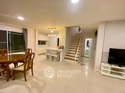 Spacious open-plan living and dining area with modern kitchen and staircase in a stylish home.