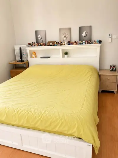 Cozy bedroom with yellow bedding and decorative shelf, perfect for relaxation.
