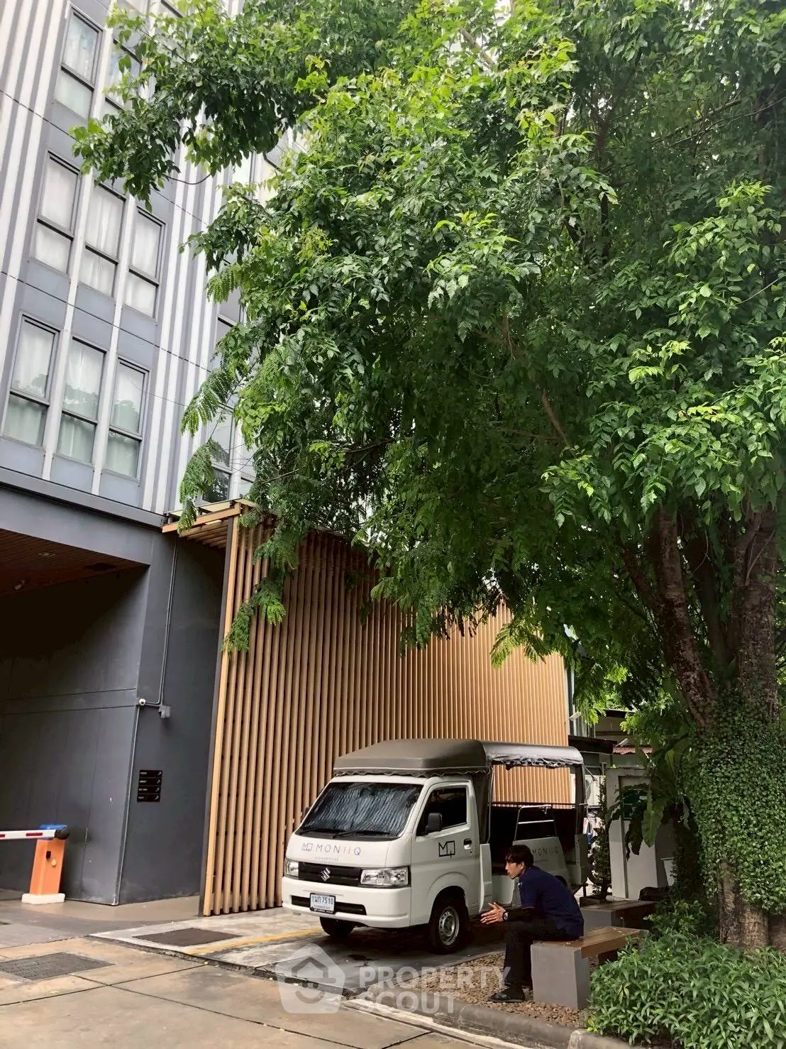 Modern building exterior with lush greenery and parked van, showcasing urban living.
